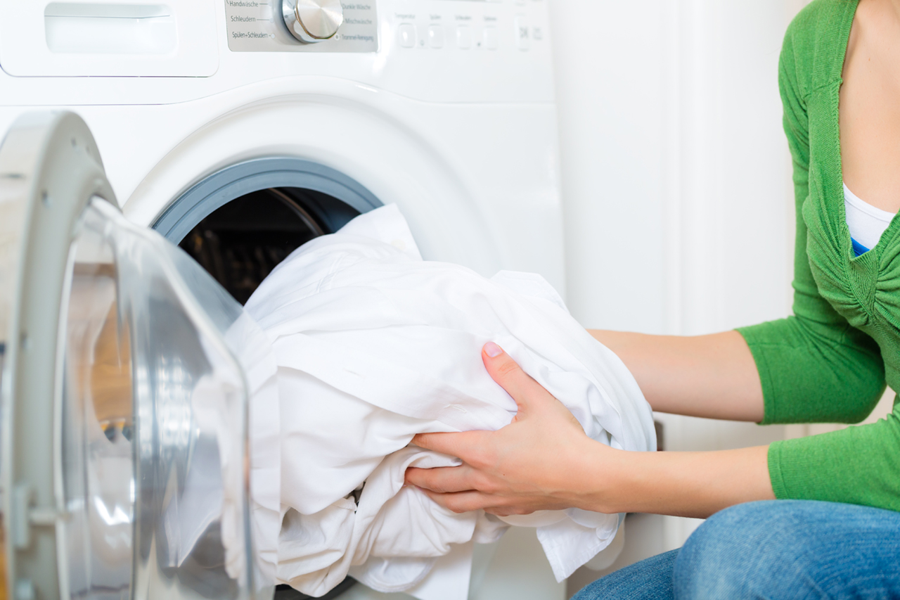 person loading laundry into the washing machine